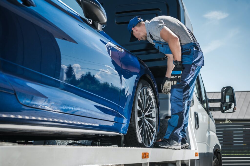 Car Repossession Worker Securing Vehicle on His Towing Truck