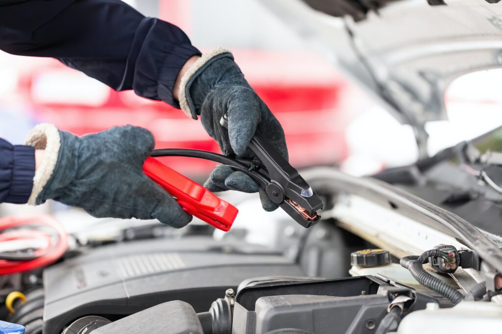Human trying to start engine with jumper cables in close up